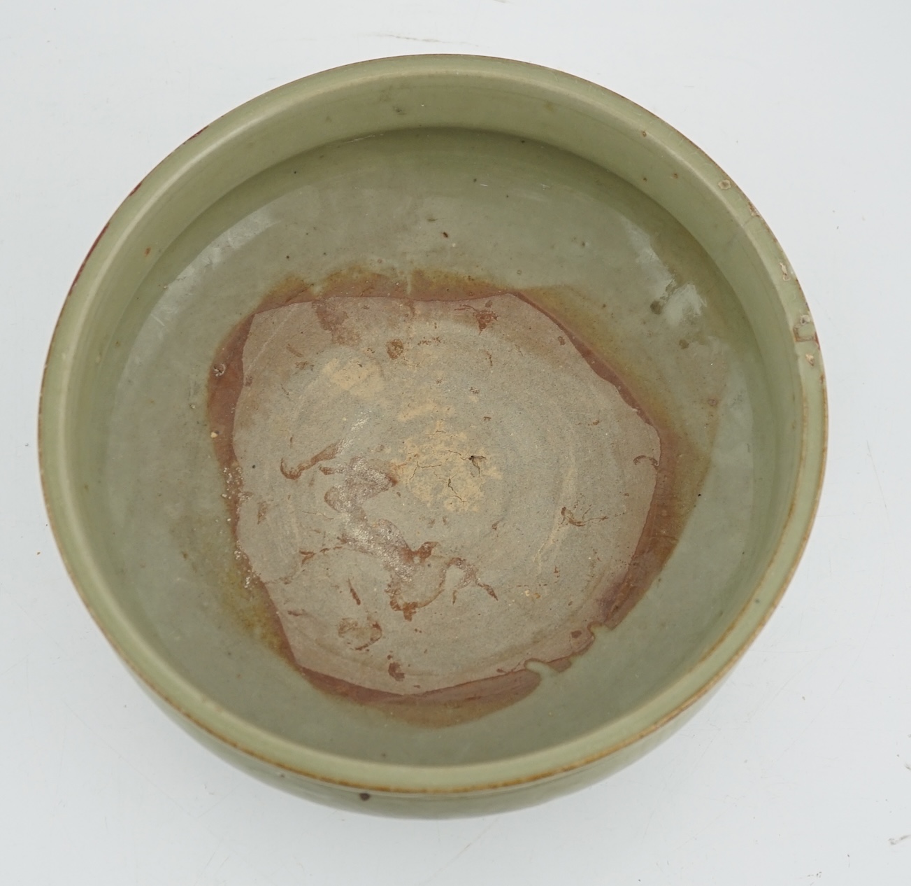 A Chinese Ming Longquan celadon tripod censer, 14th/15th century, the exterior incised with scrolling foliage, on three animal mask feet, burnt orange ring to base, 26.7cm diameter, original receipt for Wing Kei curios,